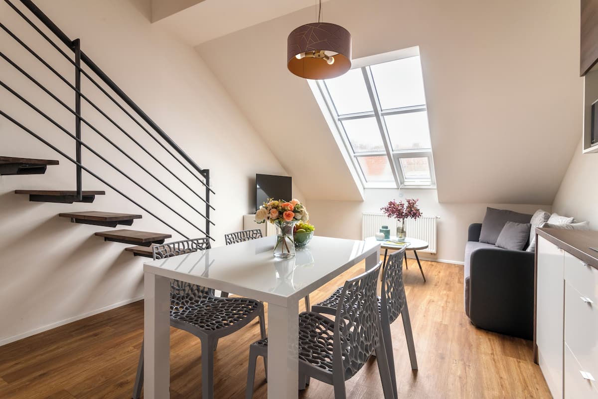 Un appartement moderne de style « loft », comprenant un coin repas, un escalier et un espace de vie.
