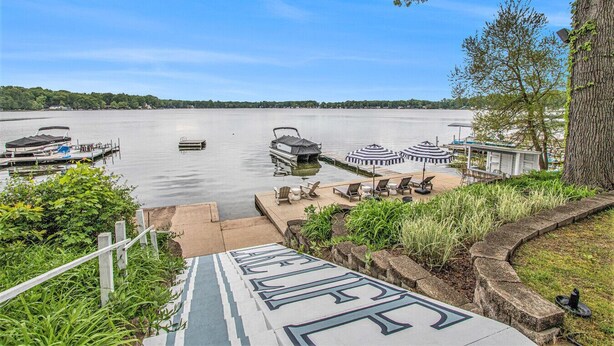 A lakeside dock with boats, a covered seating area, and a stone pathway leading to the water. - Sister Lakes 7 bedroom with Game room, Hot tub, Basketball and amazing views (Dowagiac)