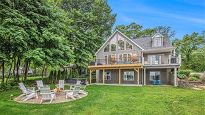 A two-story house with a large deck, a fire pit, and outdoor seating. - Sister Lakes 7 bedroom with Game room, Hot tub, Basketball and amazing views (Dowagiac)