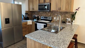 Una cocina moderna con armarios de madera, electrodomésticos de acero inoxidable, encimeras de granito y una isla integrada con lavamanos.