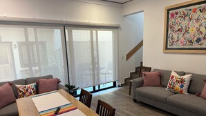 Una sala de estar moderna con una mesa de comedor, sofás y una escalera.