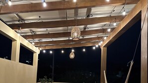 Un patio al aire libre con mesa, sillas, una hamaca y un lavamanos.