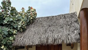 Un edificio con techo de paja, entrada con puerta de madera y un letrero que dice "Nakahwa".
