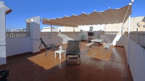 A rooftop terrace with a covered seating area, a table, and a chair. - 090 - Altomar II 005 - comfortHOLIDAYS (el Gran Alacant)