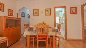 Un comedor con mesa y sillas de madera, un armario y cuadros en la pared.