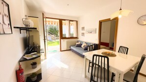 A modern kitchen with a dining area, a sofa, and a large window. - GIULY BETH'S HOUSE BRENZONE (Assenza)