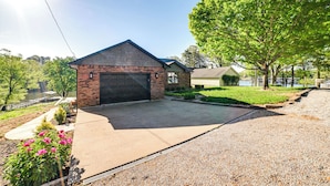 A residential property with a brick garage, a concrete driveway, and a well-maintained lawn. - Beautiful Kentucky Lake Getaway w/ Dock & Deck! (New Concord)