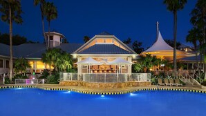 A hotel with a swimming pool, a covered bar area, and a distinctive tower.
