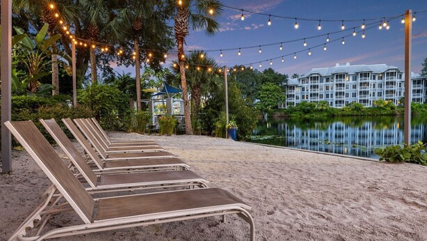 A beachside area with lounge chairs, a pool, and a building with a water view.