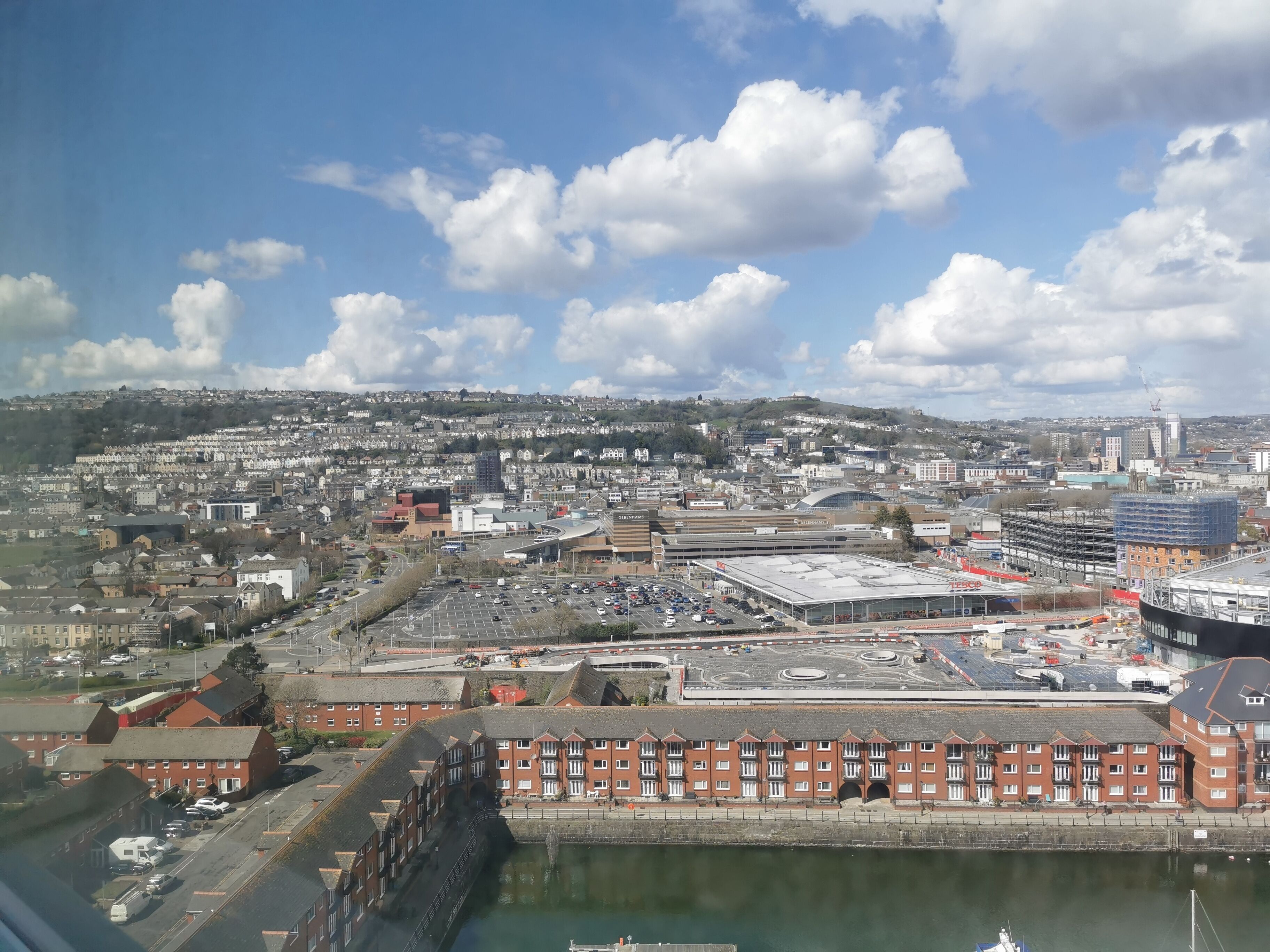A coastal cityscape with a marina, industrial buildings, and residential areas.