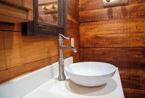 Une salle de bain avec un mur en bois, un lavabo blanc et un miroir.