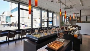 Un área de desayuno moderna con servicio tipo bufé, ventanas amplias y asientos.
