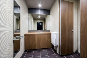 A modern bathroom with a wooden vanity, a mirror, and a sink.