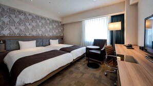 Habitación de hotel con dos camas, un escritorio, una silla, un televisor y una ventana con cortinas.