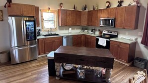 A kitchen with wooden cabinets, stainless steel appliances, and a central island. - Sanctuary Parish 18Ft ceilings, 5 bedrooms, & 3 baths (Danbury)