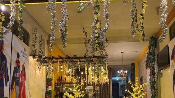 Un hall de hotel con un sofá amarillo, decoraciones florales colgantes y un cartel de Hotel Carnaval.
