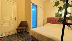 Un dormitorio con cama, una silla y una puerta que da a un baño.