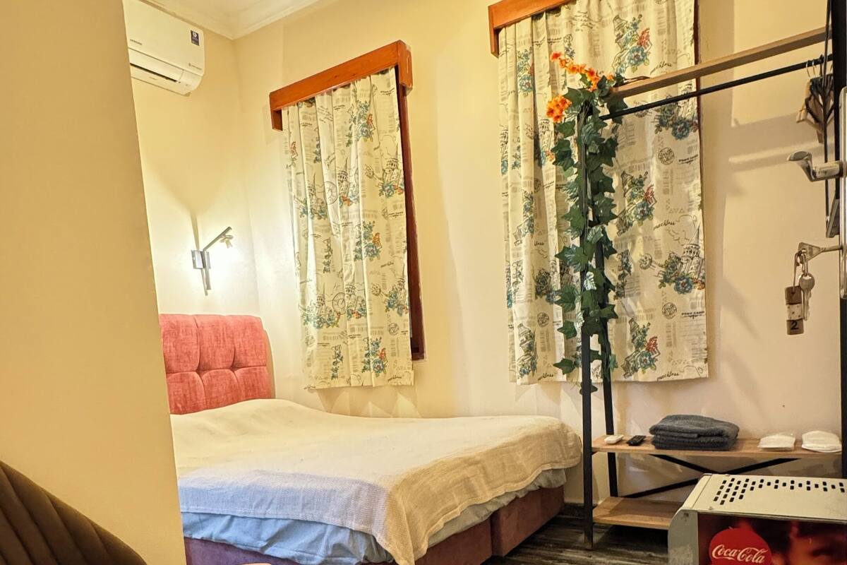 Ein Hotelzimmer mit einem Bett, einem Sessel, Holzboden und einer Wand-Klimaanlage.