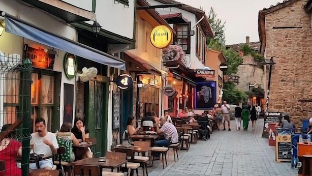 Una calle adoquinada flanqueada por edificios tradicionales, con terrazas de cafés y paseantes.