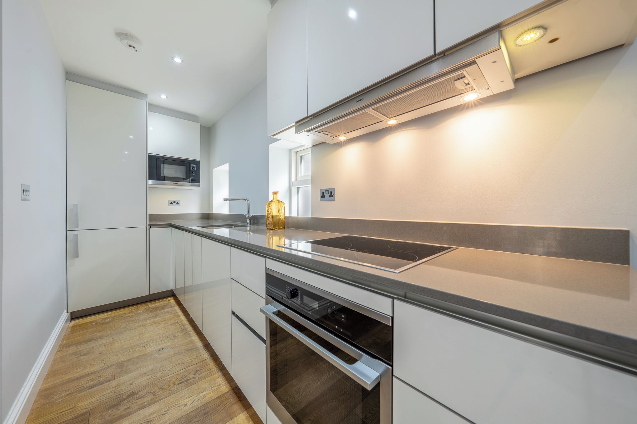 A modern kitchen with stainless steel appliances, a built-in microwave, and a large window.