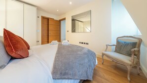 Una camera da letto con un letto, una sedia, un armadio e uno specchio.
