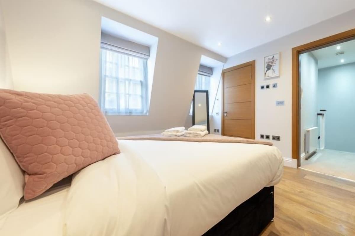 Quarto com cama grande, janela, porta e espelho.