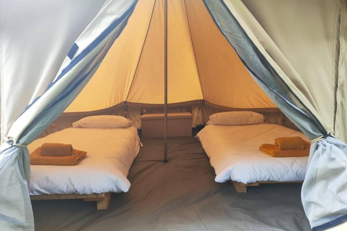 Una carpa con dos camas, cada una con almohadas y una toalla doblada.