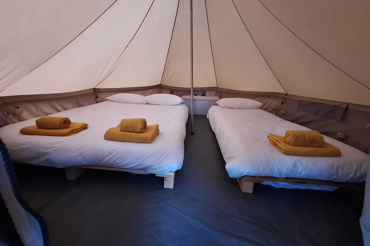 Una carpa con dos camas, cada una con una toalla enrollada.