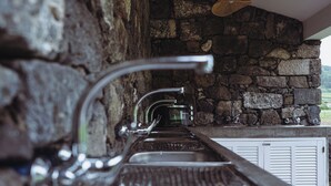 A stone wall with a built-in sink and faucet. - Bearsu Nature Almoxarife (Horta)
