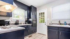 Una cocina moderna con armarios oscuros, horno integrado, microondas y estufa a gas.