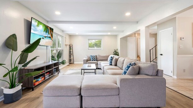 Una sala de estar moderna con un sofá seccional, un televisor de pantalla plana y una estantería.