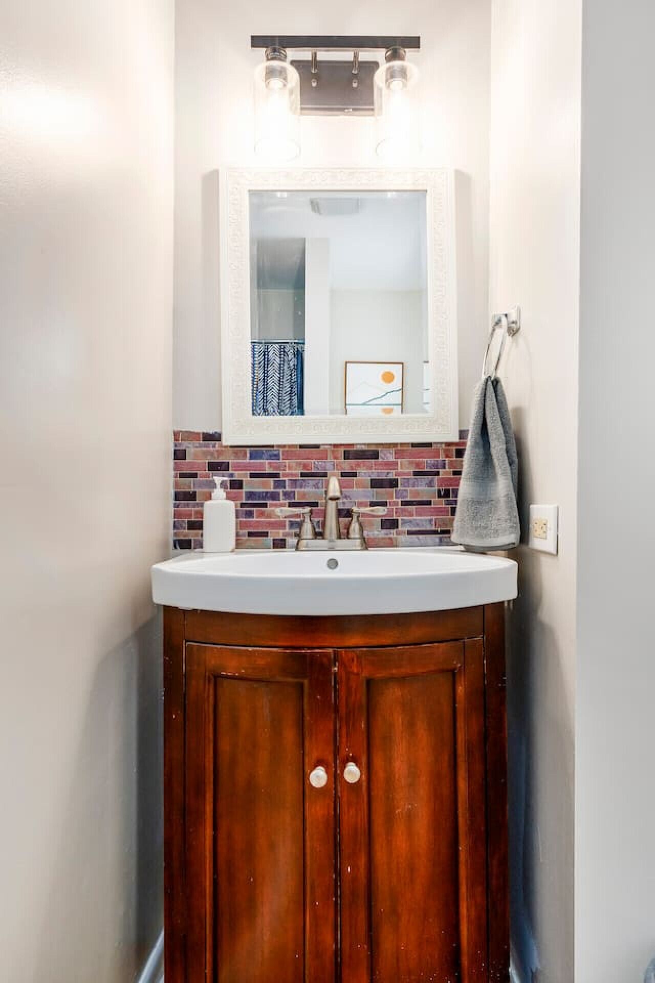 Une salle de bain avec un meuble-lavabo en bois, un lavabo blanc, un miroir et une serviette suspendue à un porte-serviettes.