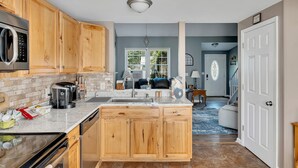 Una cucina moderna con mobili in legno, un forno a microonde in acciaio inossidabile e un forno integrato.