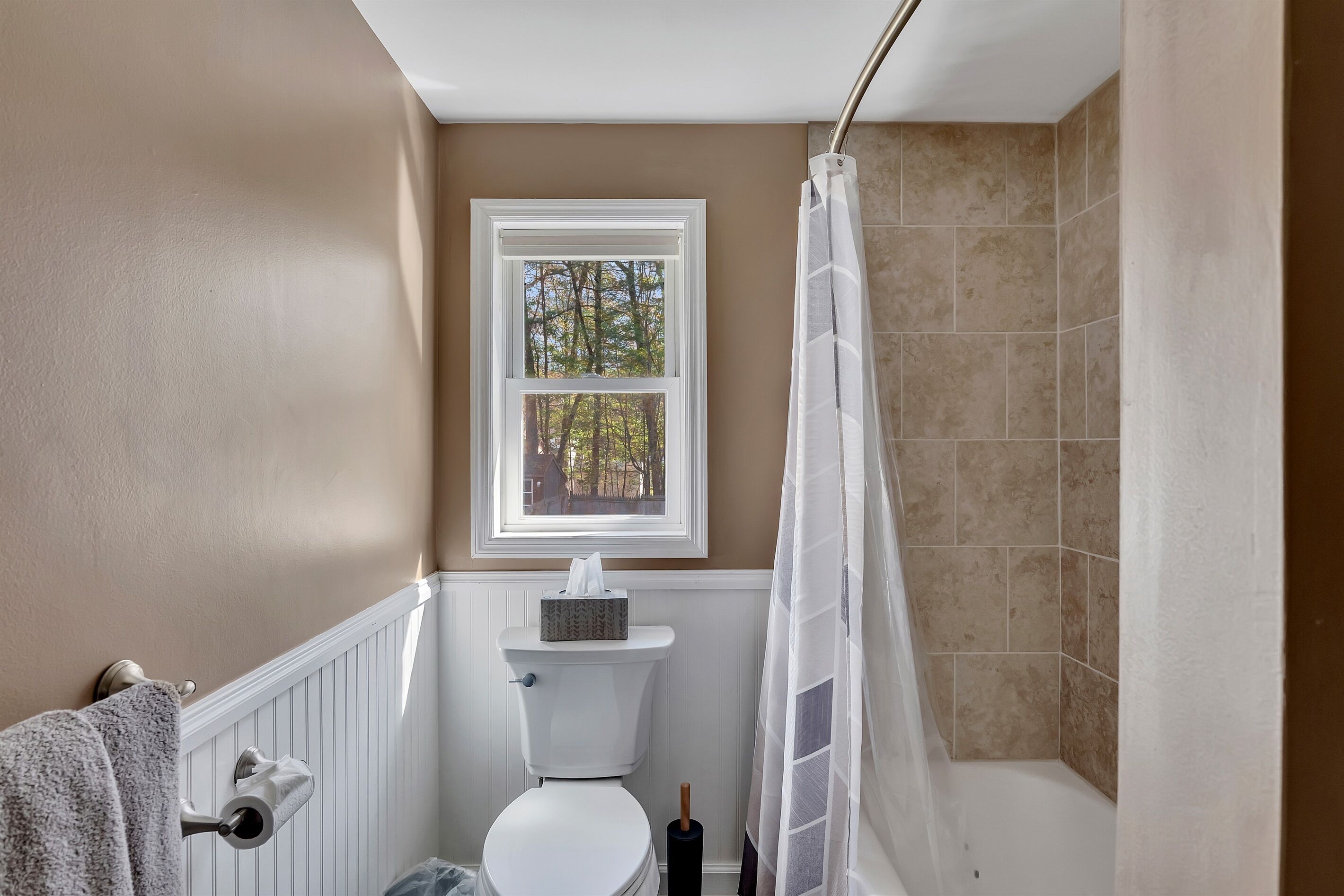 Une salle de bain avec des toilettes, une fenêtre et un espace douche.