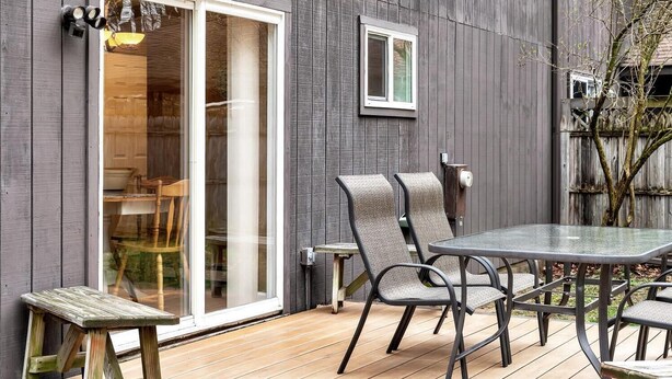 Un patio con tavolo e sedie, una porta scorrevole in vetro e un'inferriata.