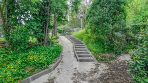 Una escalera de hormigón rodeada de abundante follaje y flores amarillas.