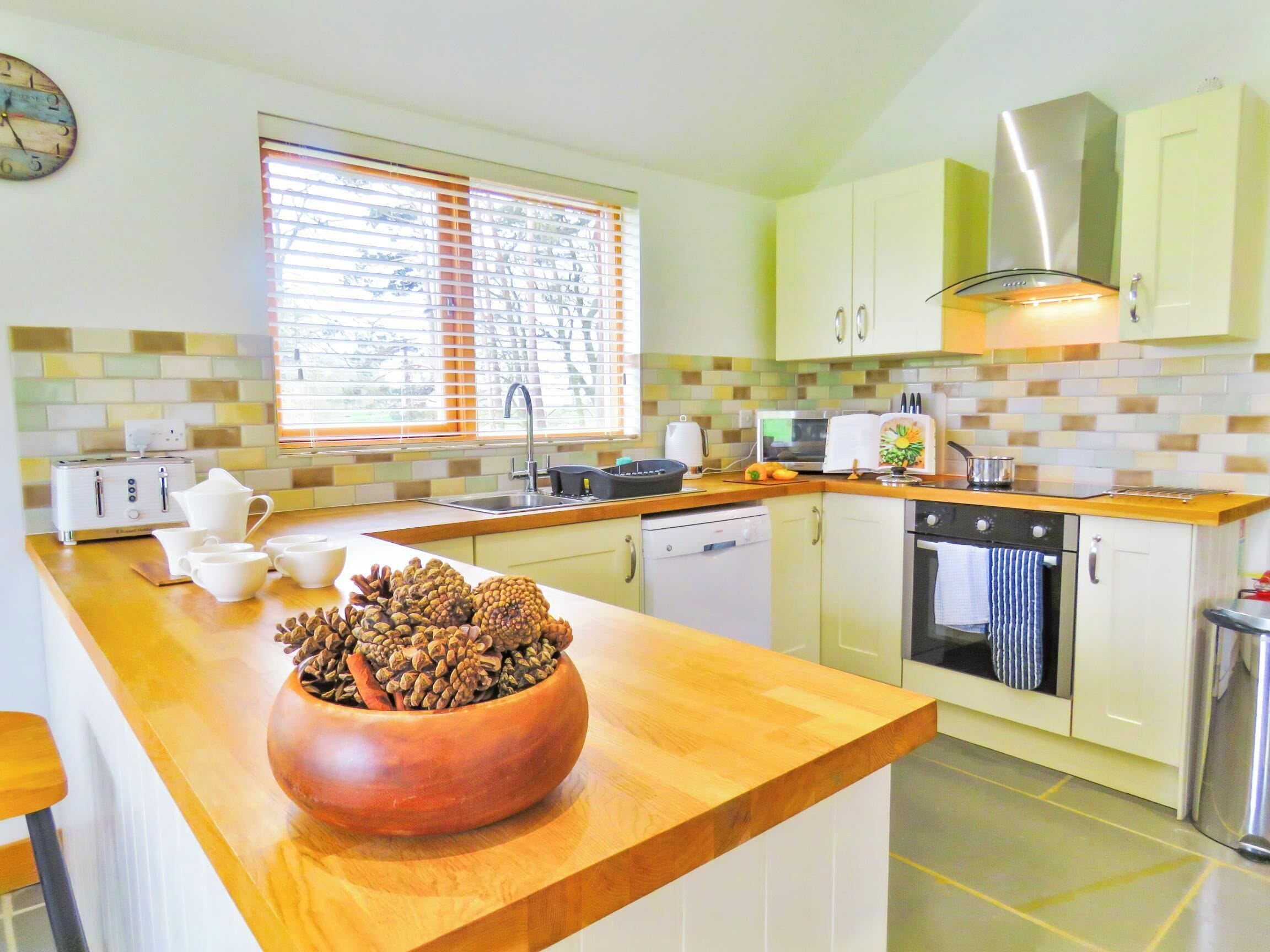 A modern kitchen with a wooden countertop, a coffee maker, a toaster, a microwave, and a stove.