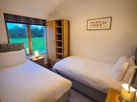 Un dormitorio con dos camas, una mesita de noche con lámpara, un armario y un cuadro en la pared.