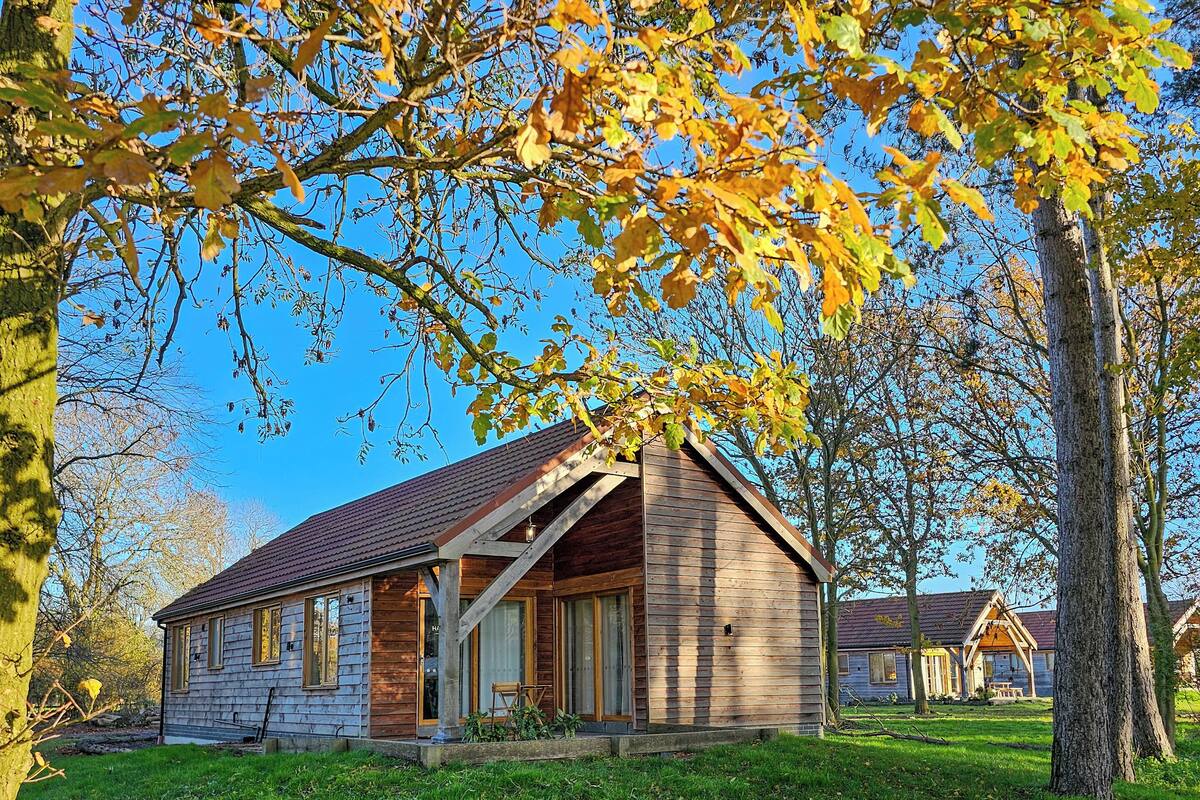 A rustic cabin with a sloped roof, wooden exterior, and a porch with a bench.