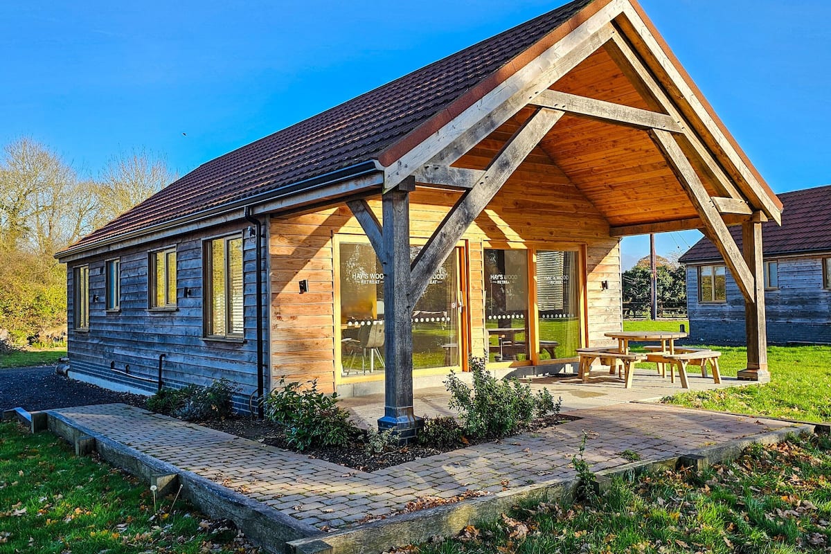 A wooden cabin with a covered patio, large windows, and a sign indicating a retreat.