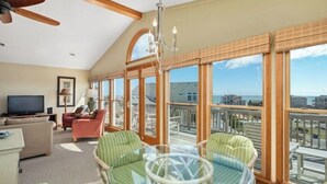 A spacious balcony with a view of the sea, furnished with wicker chairs and a glass table. - OceanSound - 500 Feet to the Ocean in Duck, NC! (Kitty Hawk)