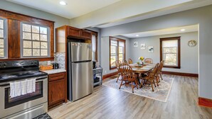 Una cocina con armarios de madera, electrodomésticos de acero inoxidable y un comedor con sillas de madera.