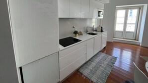 A modern kitchen with white cabinetry, a black countertop, and a small sink. - New House, Amazing View (Lisboa)