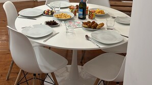 A dining area with a round table, white chairs, and a bottle of champagne. - New House, Amazing View (Lisboa)