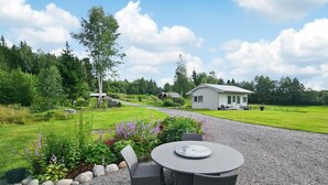 Een patio met grind, met een ronde tafel en stoelen, omringd door een tuin vol planten en bloemen.