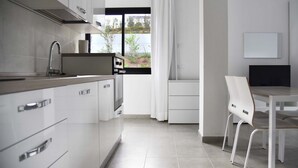 A modern kitchen with white cabinetry, a stainless steel sink, and a window with a view of greenery.