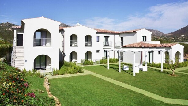 A white villa with multiple arches, a covered patio, and a well-maintained garden.