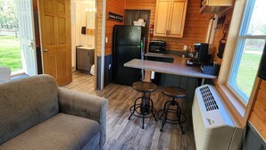 A compact kitchen with a refrigerator, microwave, and bar stools.