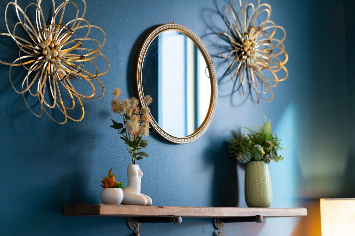 A wall with a blue color scheme, a decorative mirror, and two wall art pieces.