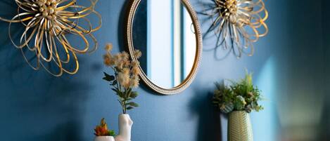 A wall with a blue color scheme, a decorative mirror, and two wall art pieces.